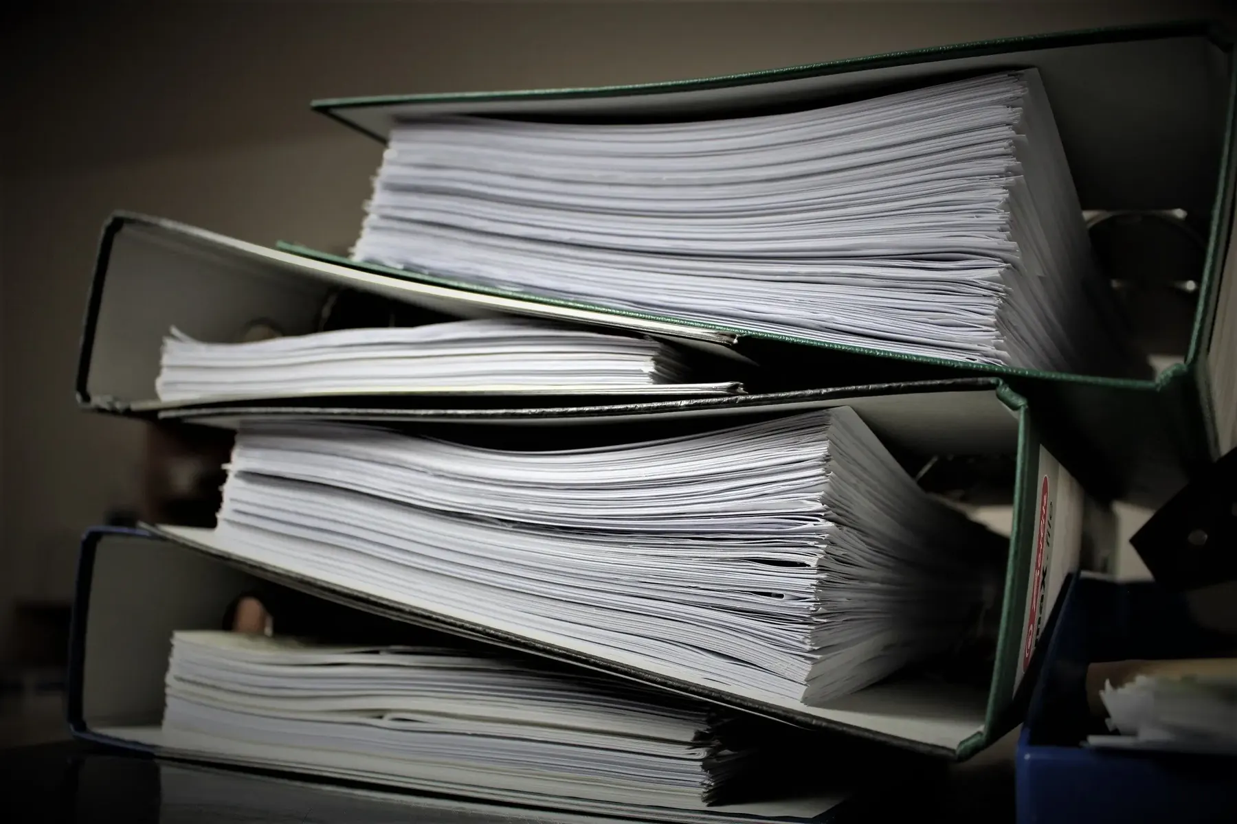 Ring binders of printed reference material stacked on a desk
