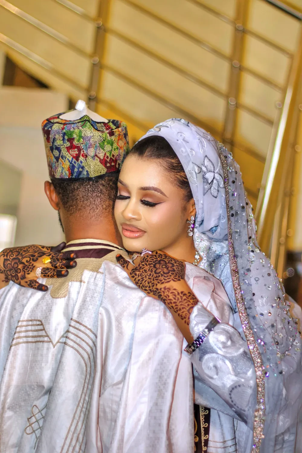 A couple in traditional Nigerian wedding dress, the bride resting against the groom's shoulder